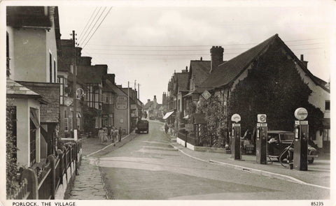 Old real photo postcard of Porlock Village, showing Esso petrol pumps