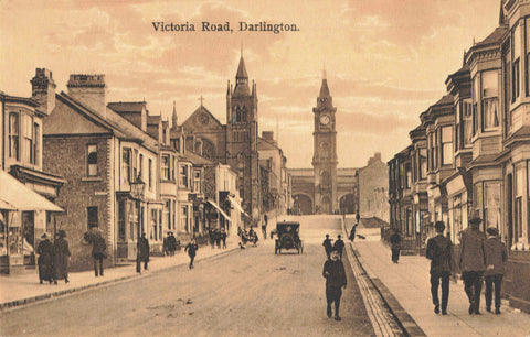 Vintage street scene of Victoria Road, Darlington with people and vehicles on the road.