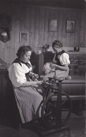Real photo postcard of a lady at a spinning wheel with a young assistant